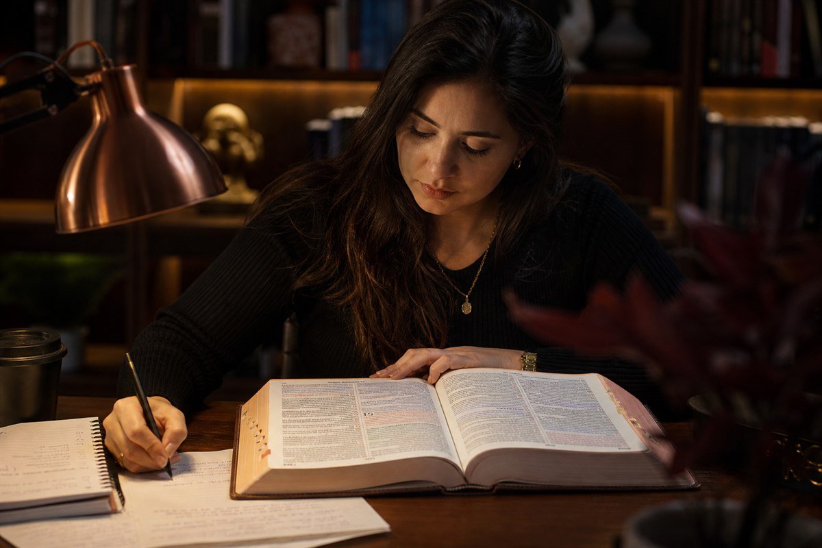 Estudante de teologia fazendo anotações diante de uma Bíblia aberta